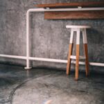 Solid oak counter stool against a concrete wall