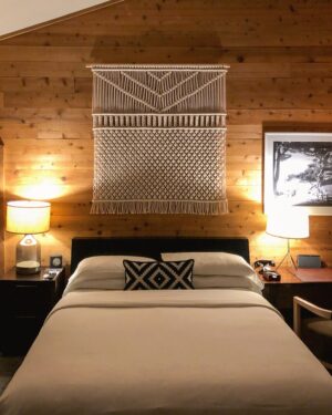 Oak king bed frame with layered bedding against a timber wall